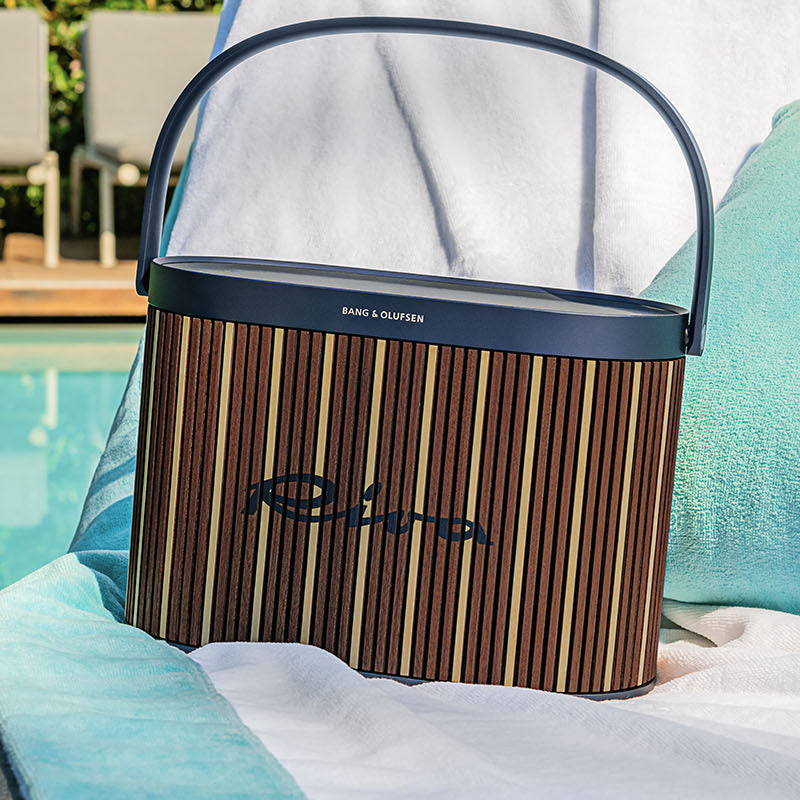 Bang & Olufsen Beosound A5 Riva Edition portable speaker with sleek design and fabric cover, shown on a wooden surface.