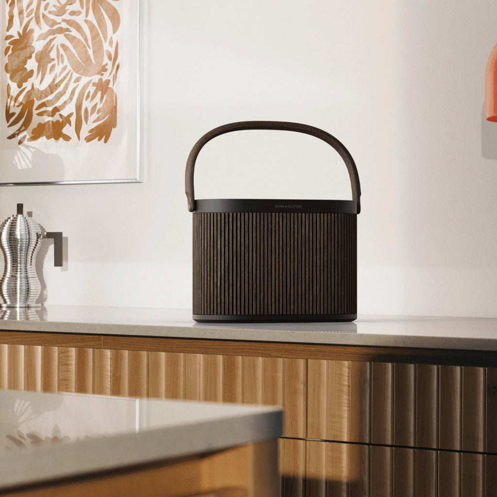 Bang & Olufsen Beosound A5 portable speaker in sleek black with fabric covering and control buttons on top, designed for high-quality sound.