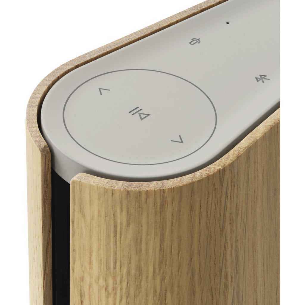 Bang & Olufsen Beosound Emerge wireless speaker in gold tone with sleek, modern design and fabric cover.