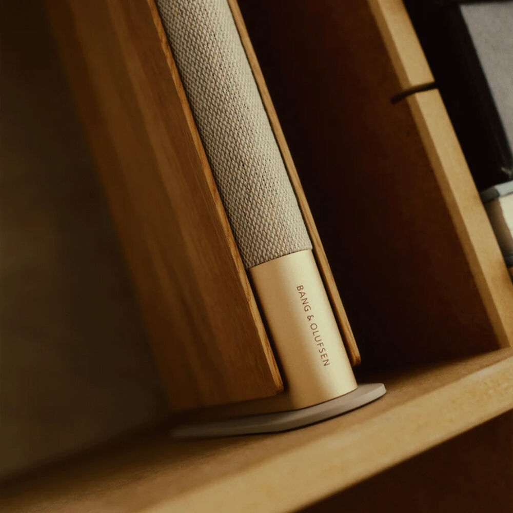 Bang & Olufsen Beosound Emerge wireless speaker in elegant gold tone, showcasing its sleek, modern design and compact size.