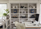 KEF LS50 Meta passive bookshelf speakers in royal blue, shown on a shelf in an office room setting.