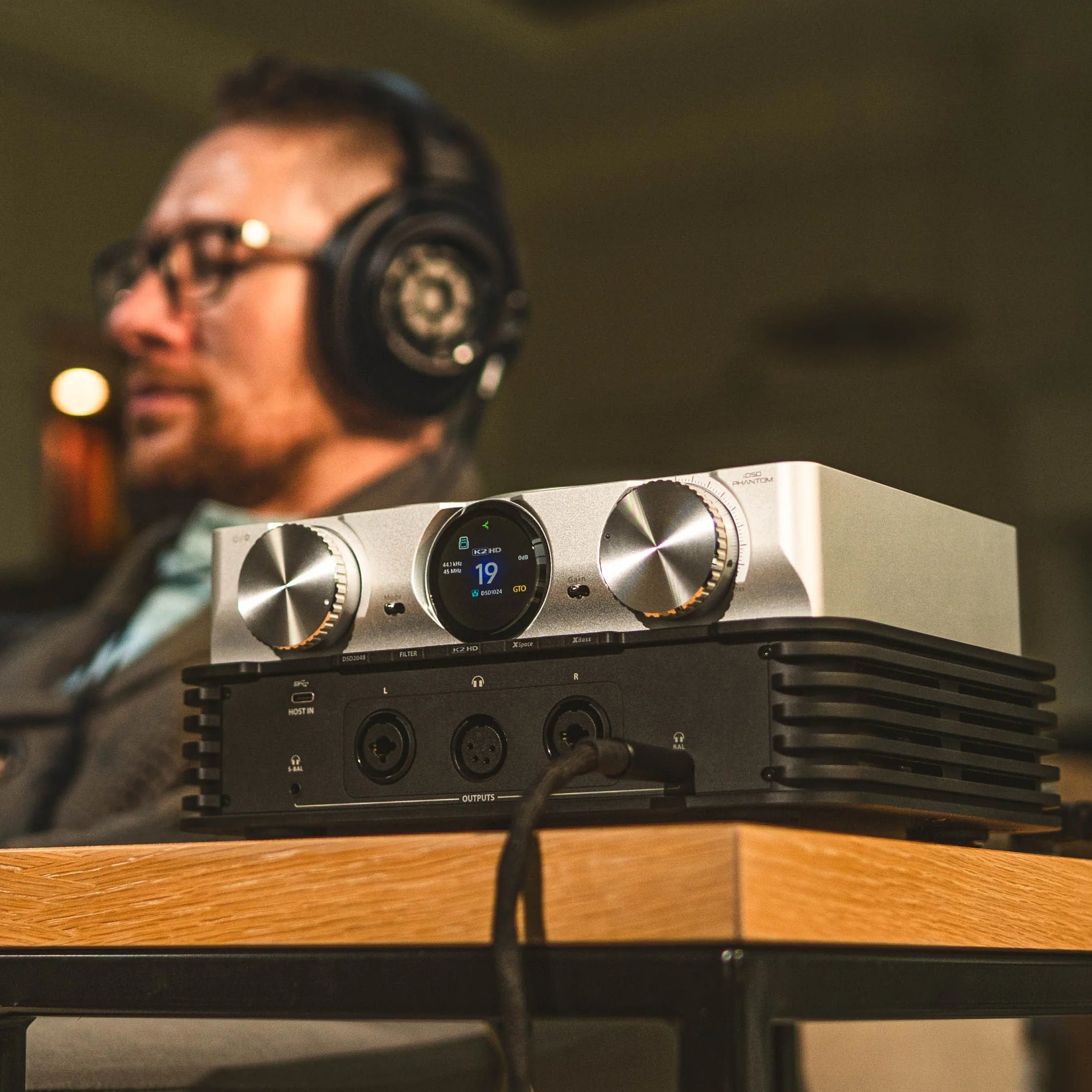 iFi Audio iDSD Phantom headphone amplifier and DAC with silver finish, showing front panel with controls and display screen.