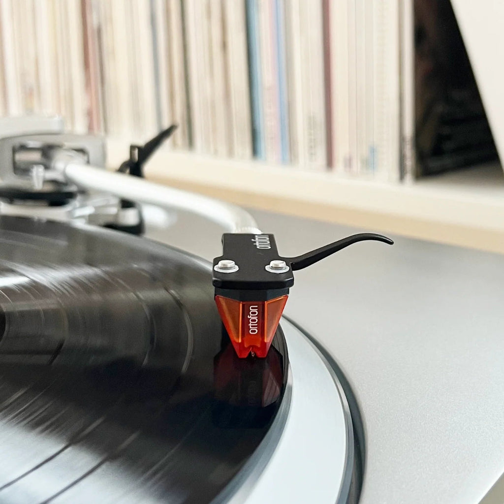 Ortofon 2M Bronze turntable cartridge with stylus, detailed close-up showing its metallic body and stylus tip for high-quality audio.