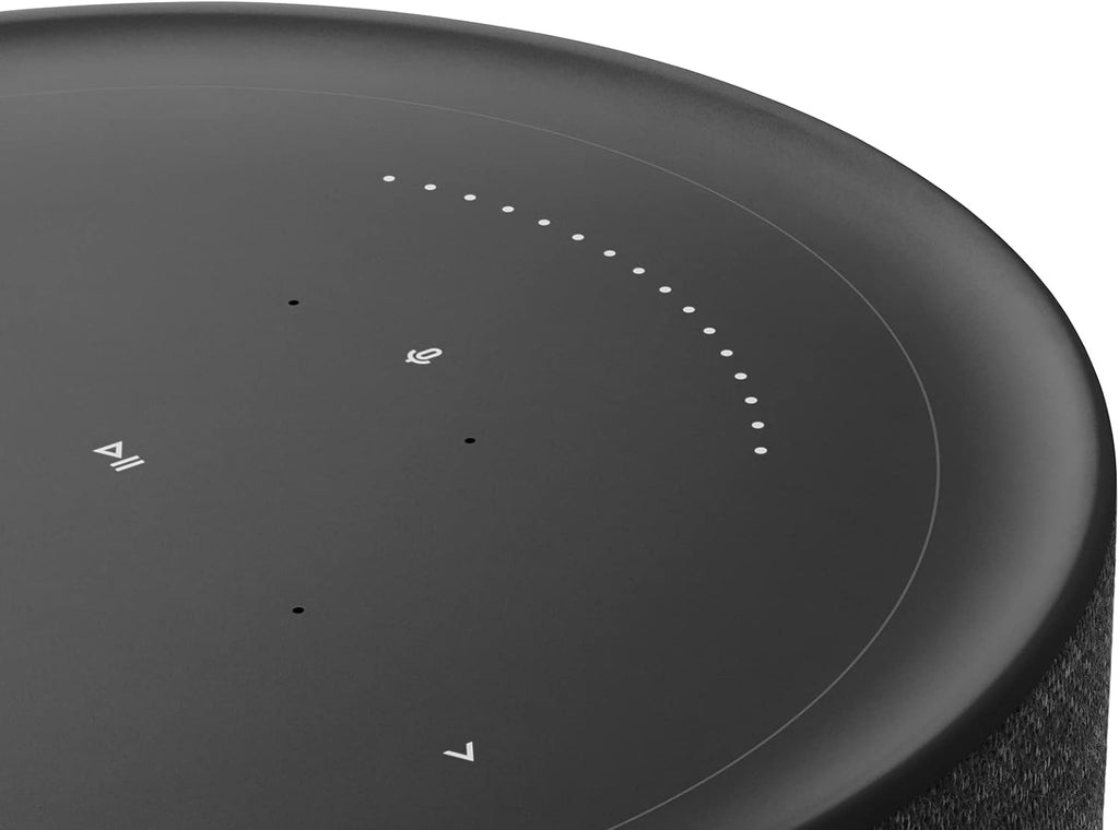 Bang & Olufsen Beosound Balance wireless speaker with sleek design and control buttons, set on a wooden surface.
