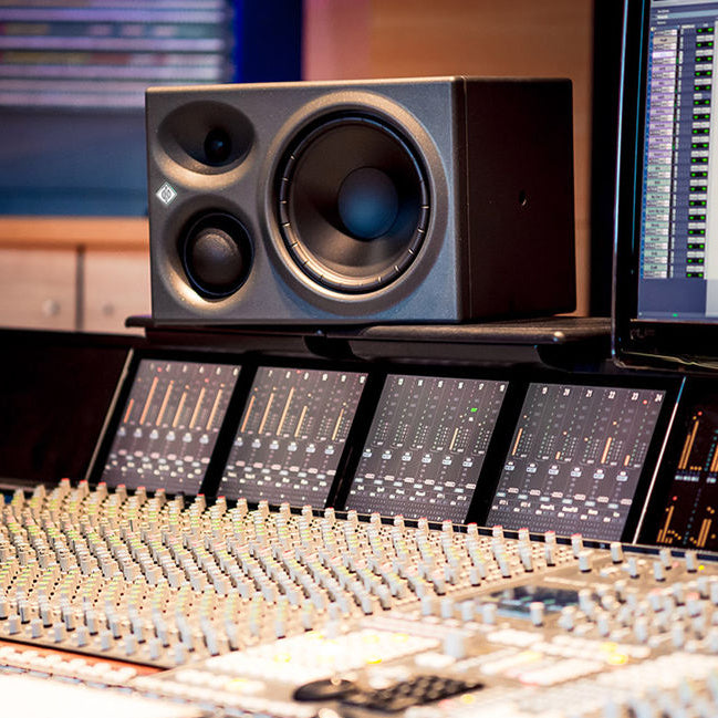Neumann KH 310 A L G mid-field monitor speaker showing a sleek black finish and front grille for professional audio setup.