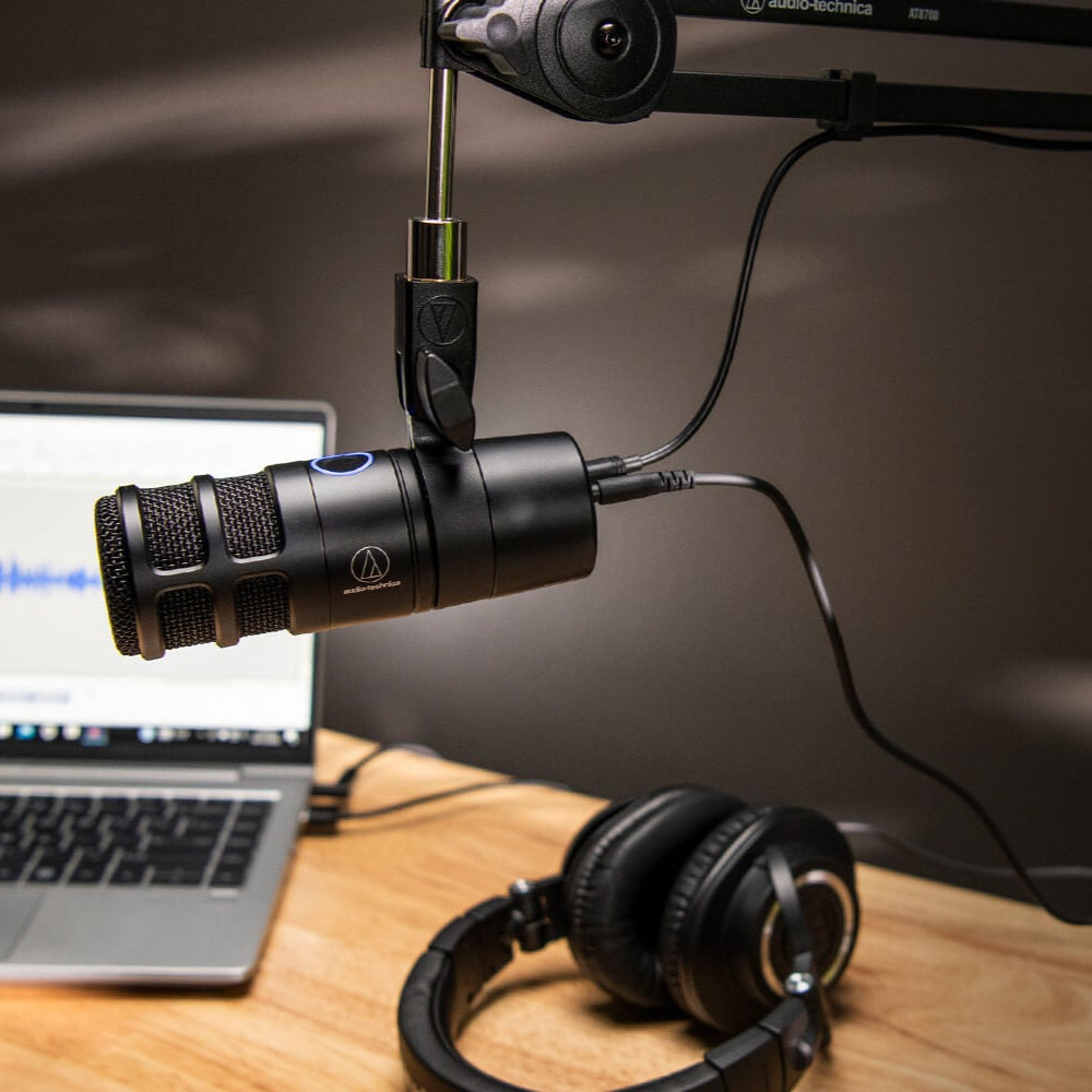 Audio-Technica AT2040USB USB microphone on a desk with a computer setup, ideal for streaming and podcast recording.
