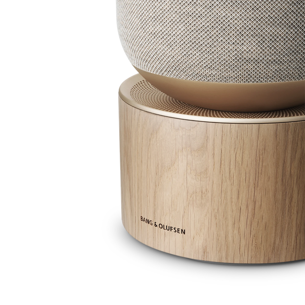 Bang & Olufsen Beosound Balance wireless speaker in natural wood finish with sleek design and control knobs visible.