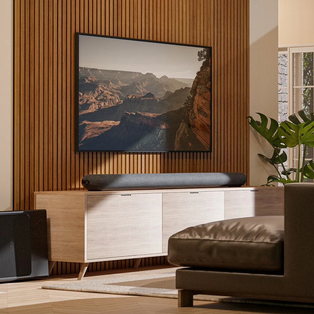 Bluesound Pulse Cinema soundbar with sleek design and integrated TV speakers, shown in a modern living room setting.