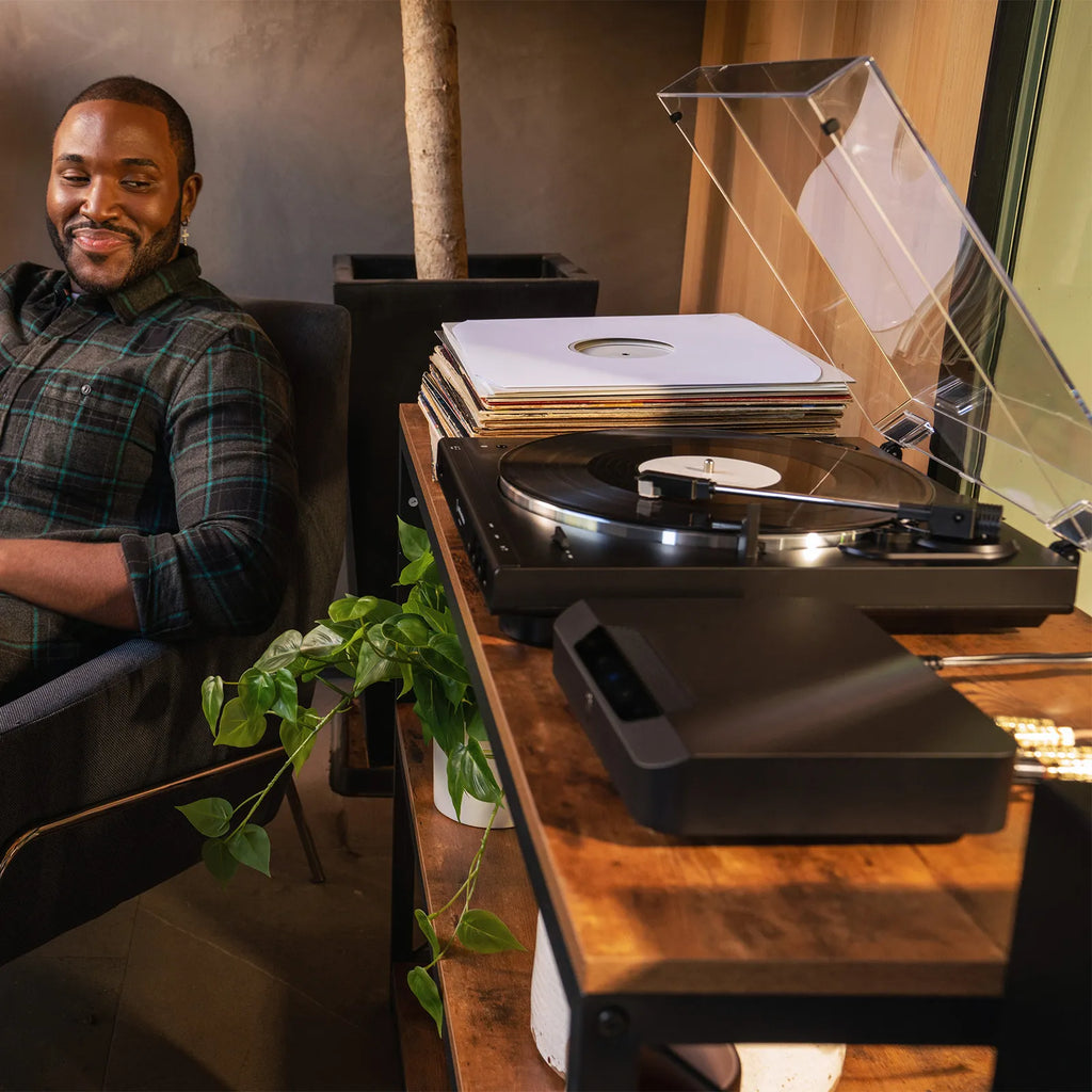 Bluesound Powernode Edge music streamer connected to a turntable, showcasing high-quality audio streaming technology.