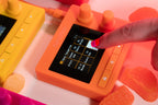 Desktop view of 1010music Nanobox Tangerine drum machine and sampler with colorful interface and control knobs.