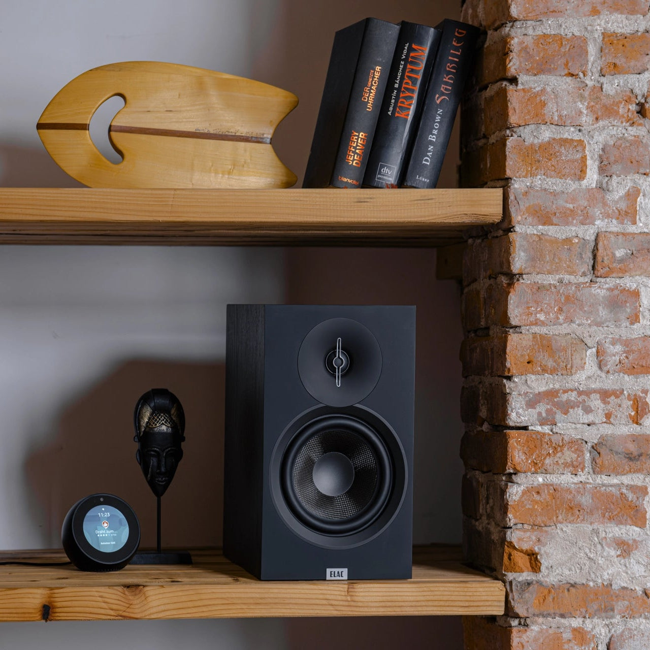 ELAC Debut B5.3 passive bookshelf speakers shown in a modern living room setting with wood finish and speaker grilles attached.