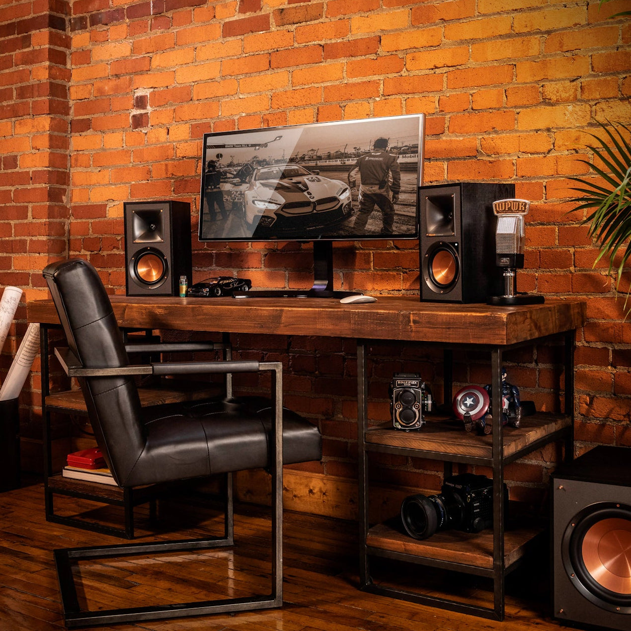 Klipsch R-41PM active bookshelf speakers with wood finish and front control panel, positioned on a modern audio setup.