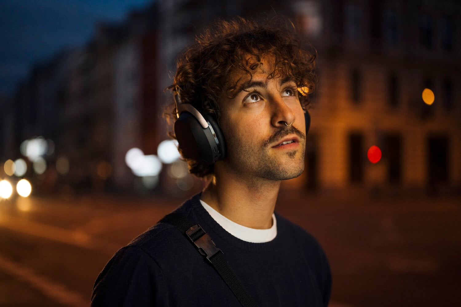 Wireless Beyerdynamic Aventho 300 headphones worn by a city guy in dark lighting, showcasing their sleek design.