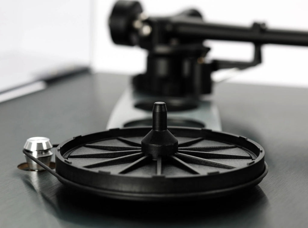 Close-up of Rega Planar 3 RS turntable with aluminum platter and Nd5 cartridge, showing the hub bearing and tonearm details.