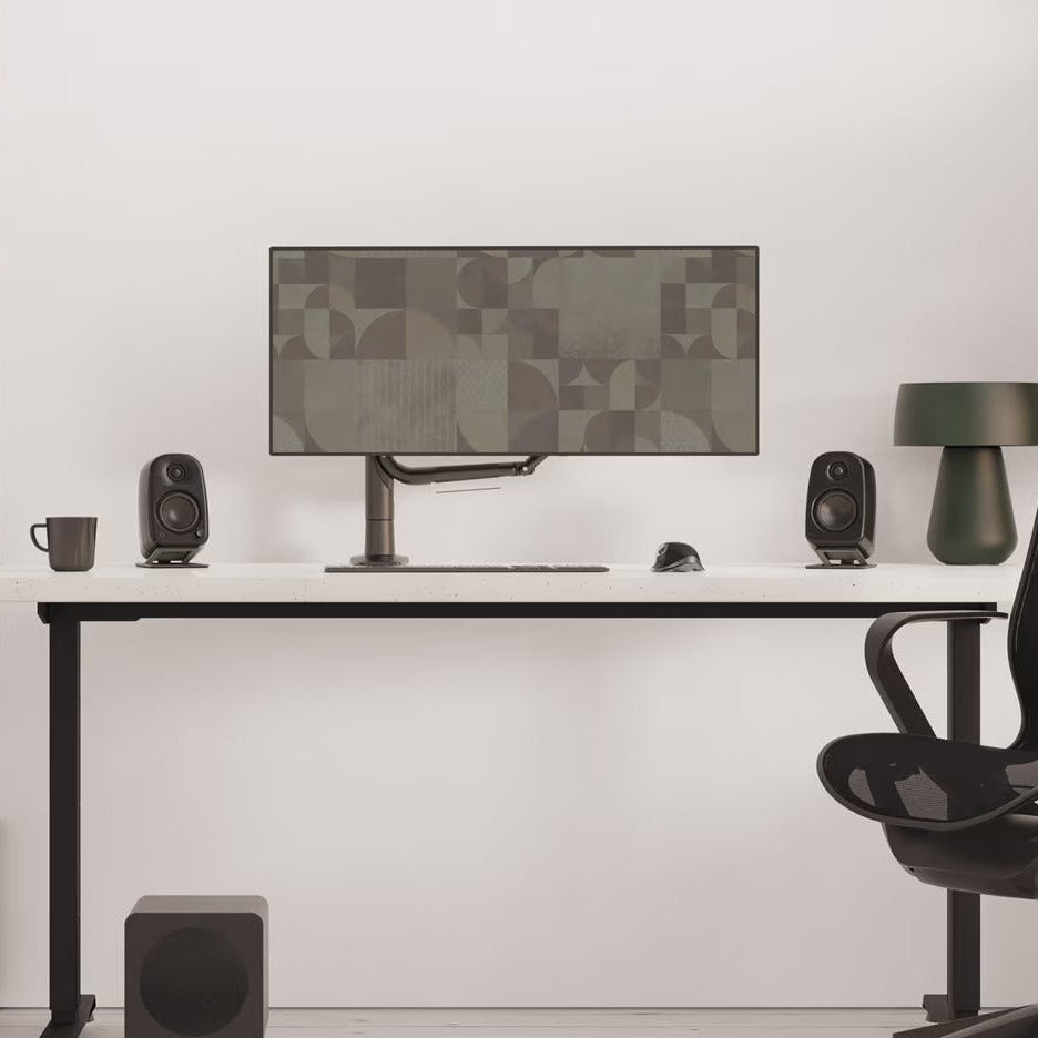 Kanto Audio UKI desktop speakers in a modern workspace, showcasing sleek design and compact size for high-quality sound.