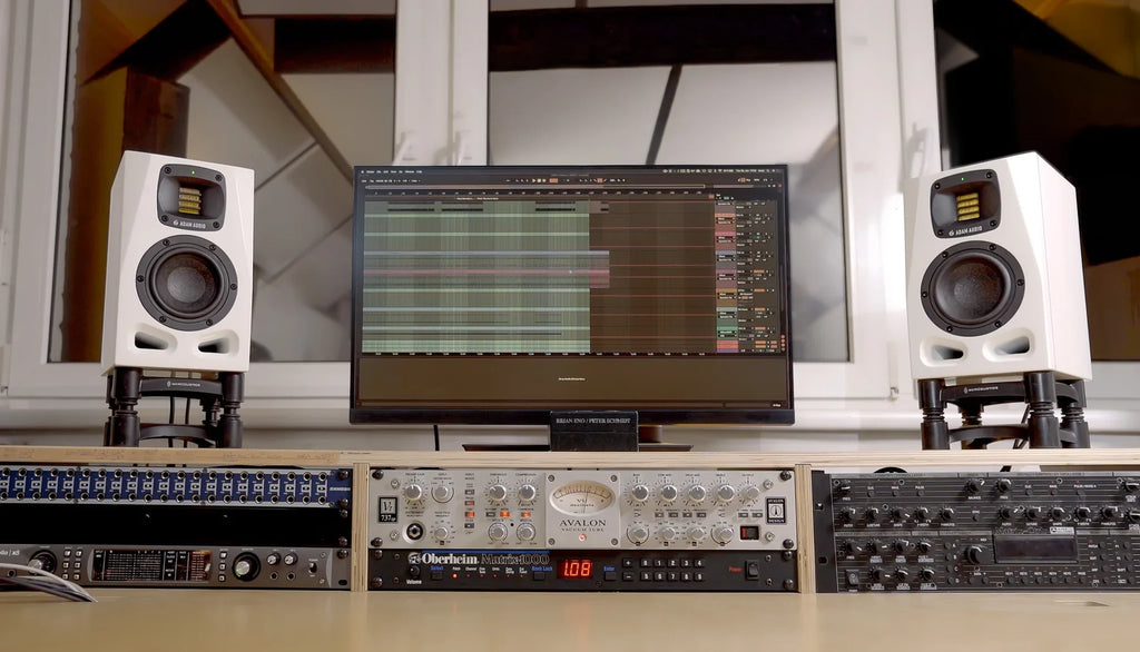 Pair of Adam Audio A4V active nearfield studio monitors shown on a desk in a limited edition 25th anniversary lifestyle image.