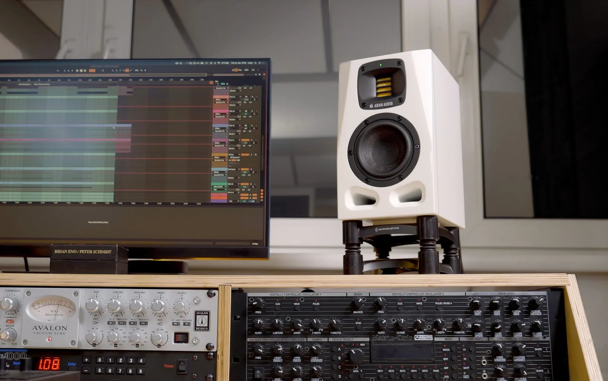 Adam Audio A4V active nearfield studio monitors in a lifestyle setting, showcasing the sleek black finish and compact design.