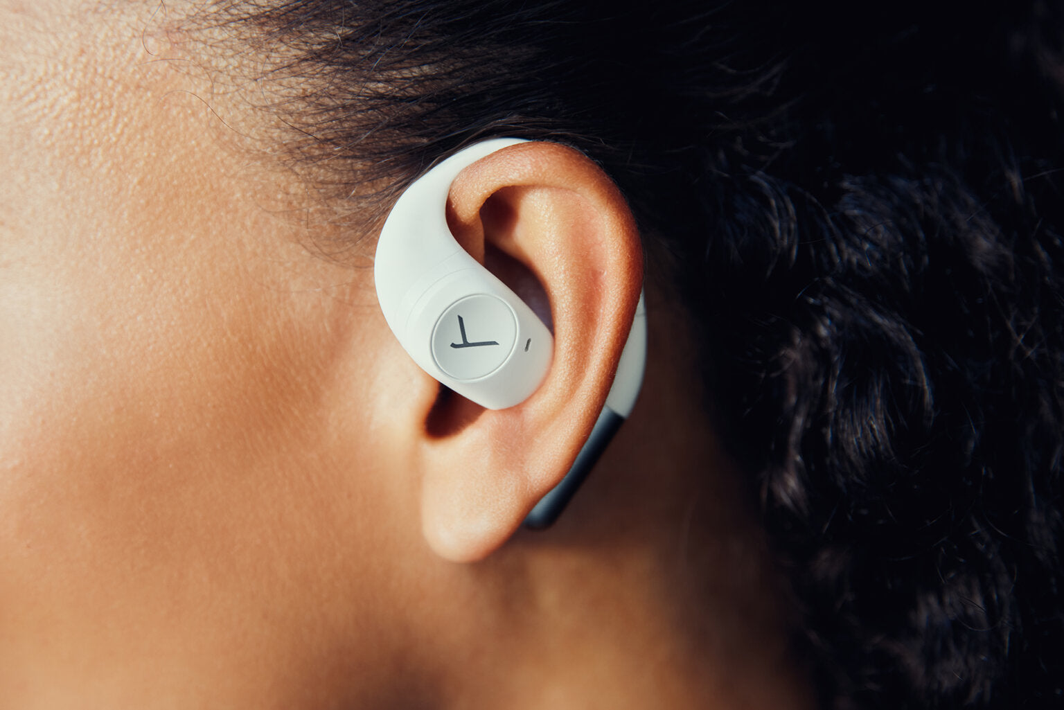 Close-up of white Beyerdynamic Amiron 200 wireless in-ear headphones worn by a woman.