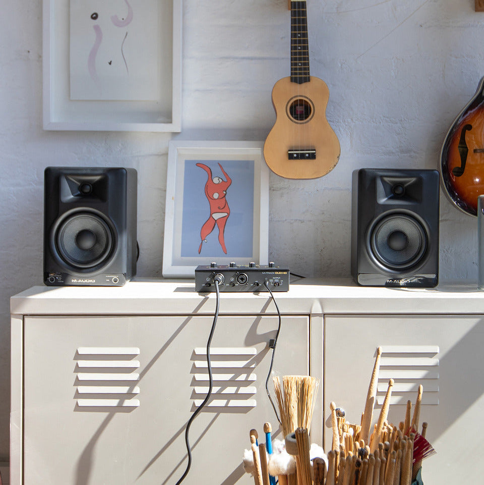 M-Audio BX5 BT active nearfield monitors on a desk, showcasing compact design and Bluetooth connectivity for professional audio.