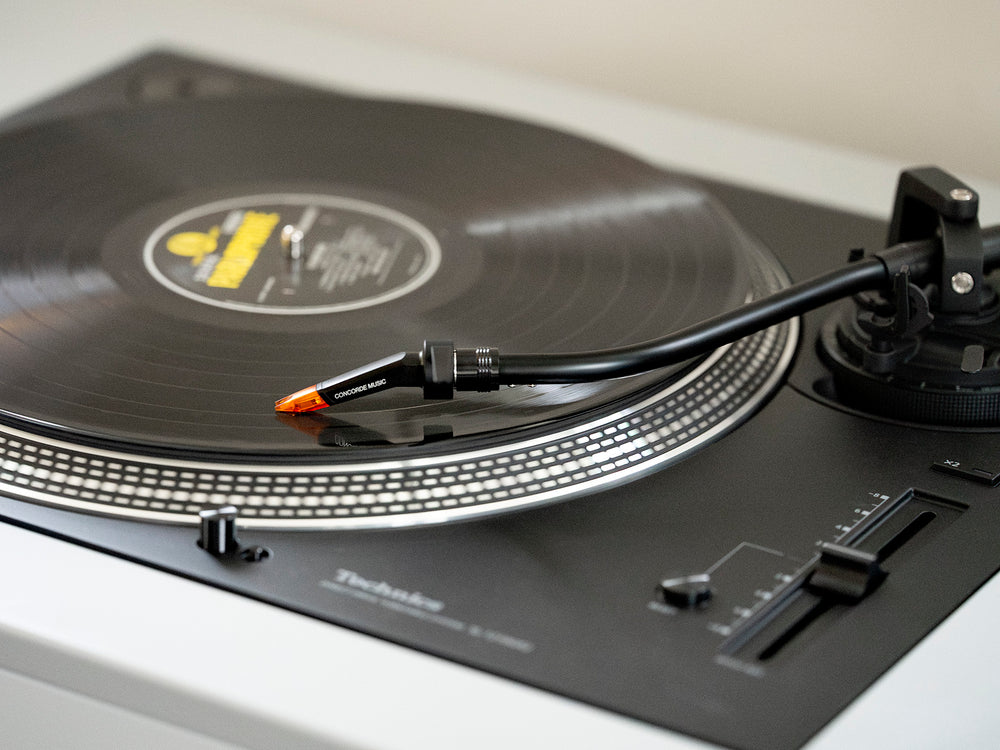 Ortofon Concorde Music Bronze turntable cartridge mounted on a Technics turntable, close-up view of the cartridge and stylus.