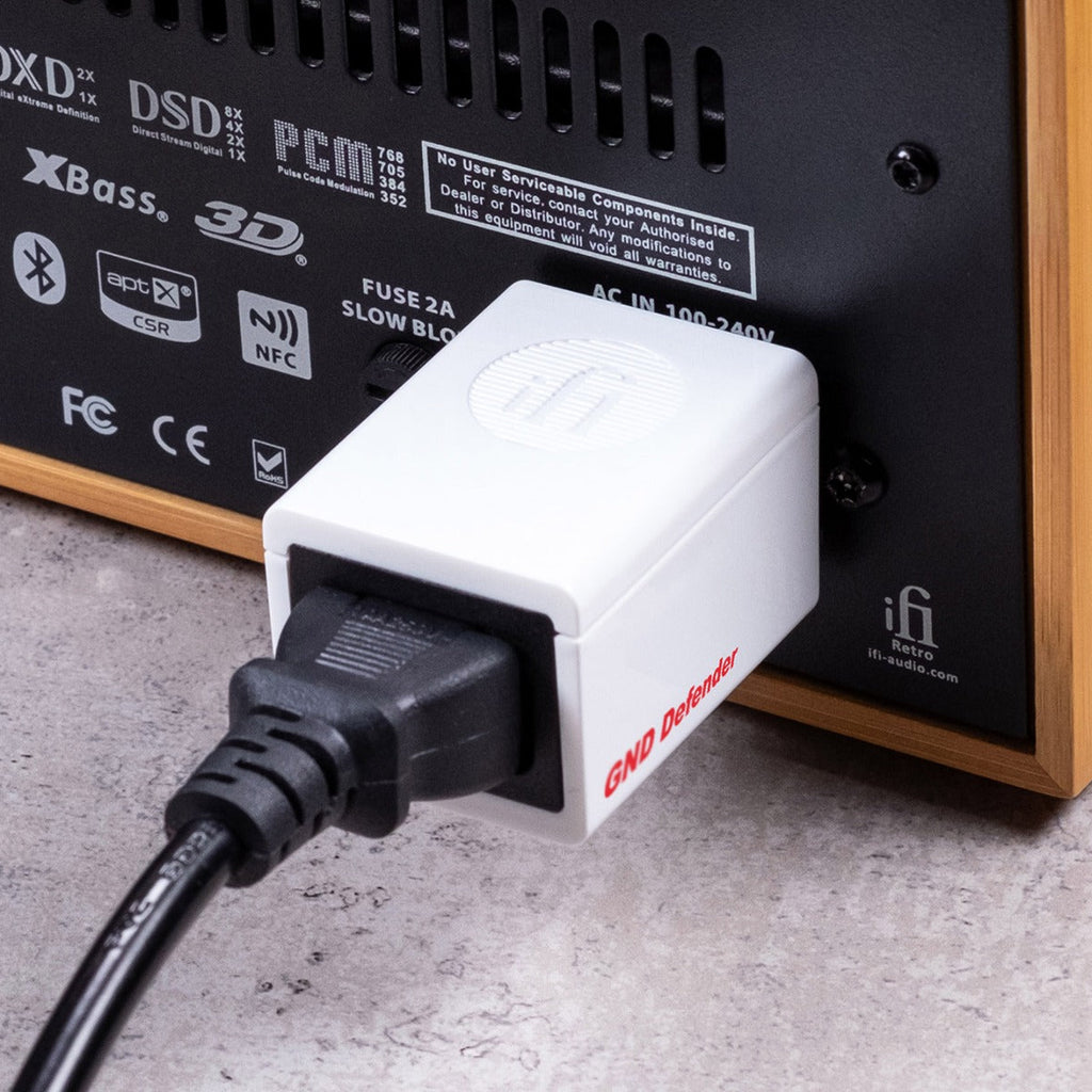 iFi Audio GND Defender connected to audio equipment, showcasing its compact design and utility in reducing noise interference.
