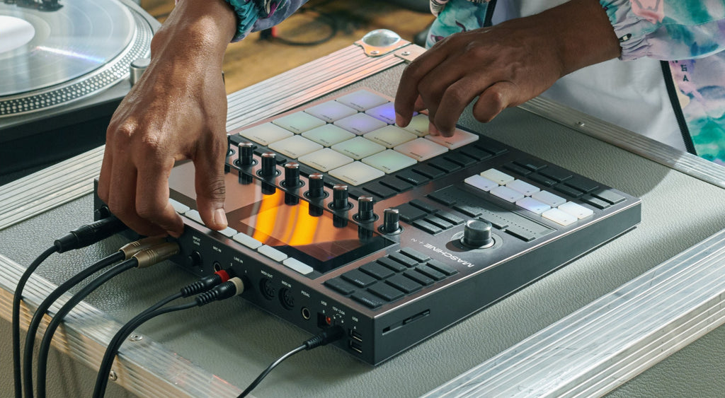 Native Instruments Maschine+ drum machine and sampler with colorful pads and interface for music production.
