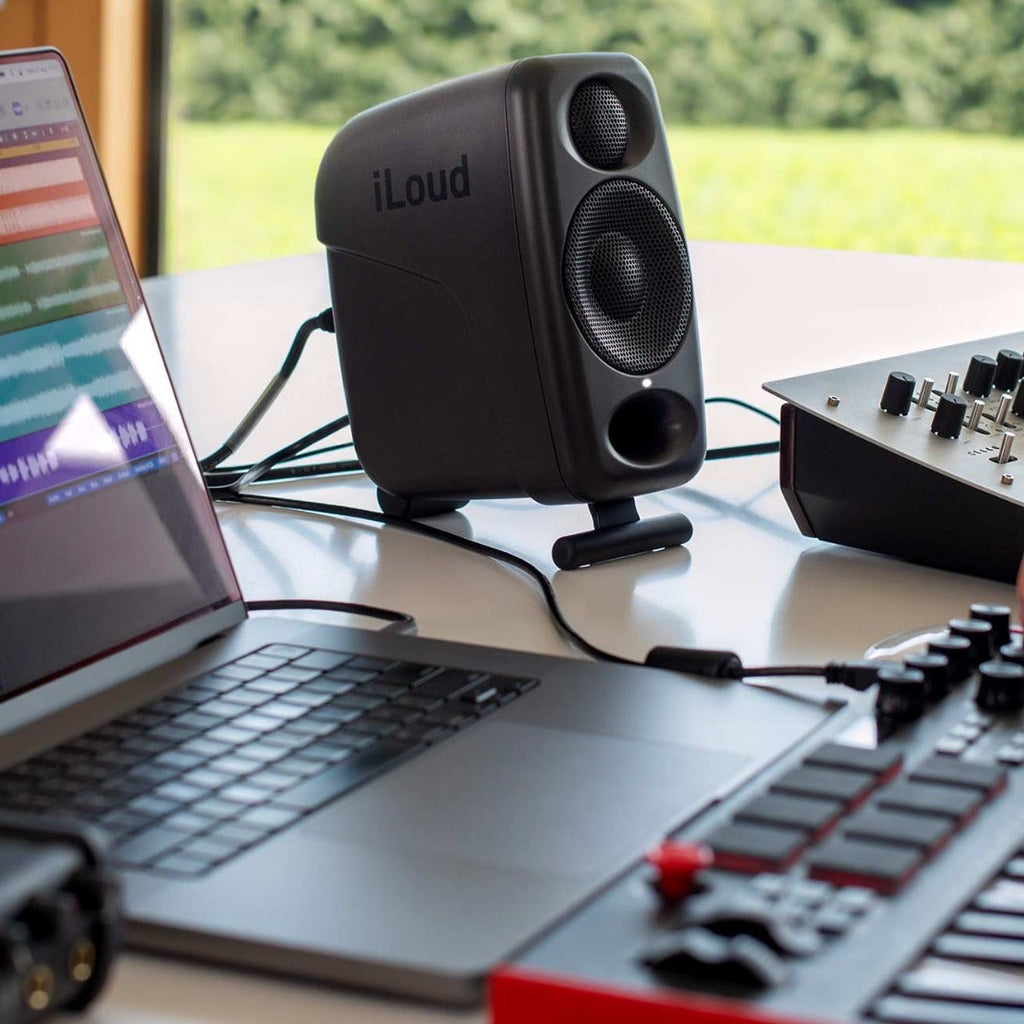 IK Multimedia iLoud Micro Monitor Pro active nearfield speakers on a studio desk with controls and cables visible.