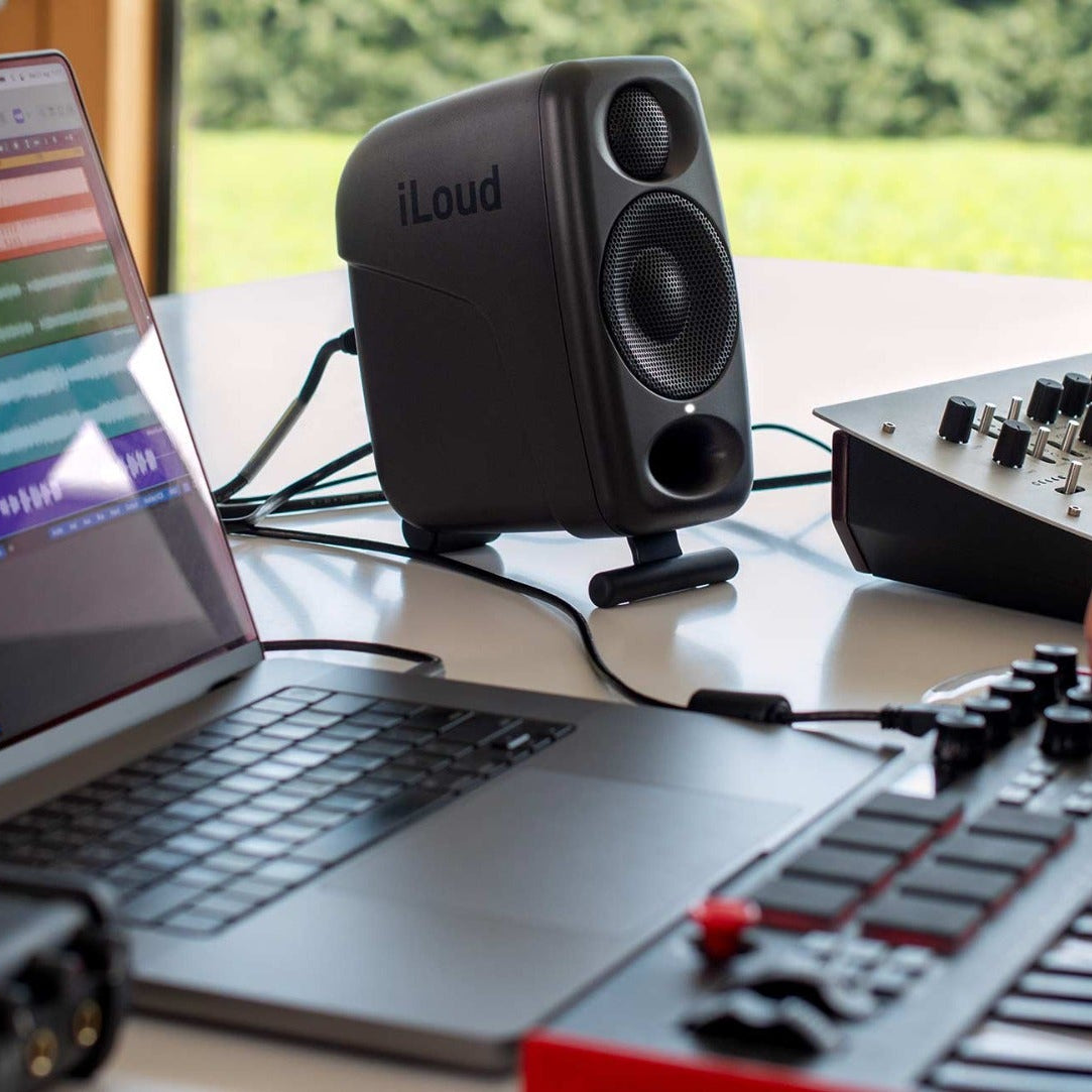 IK Multimedia iLoud Micro Monitor Pro active nearfield speakers on a studio desk with controls and cables visible.