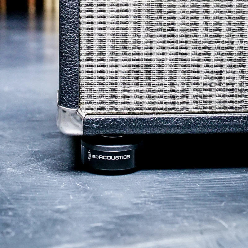 IsoAcoustics ISO-Puck studio monitor stands on a surface, designed to isolate and reduce vibrations for guitar and bass amps.