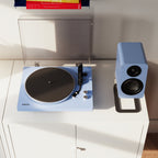 Kanto Audio OBI3 Gen 2 turntable, Ice Blue, on a white sideboard with matching speaker