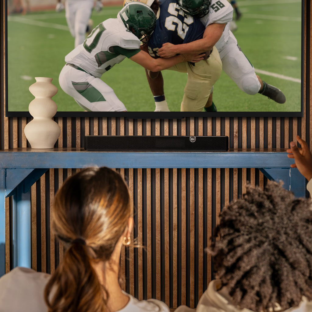 Klipsch Flexus Core 100 soundbar, on stand under TV football game.