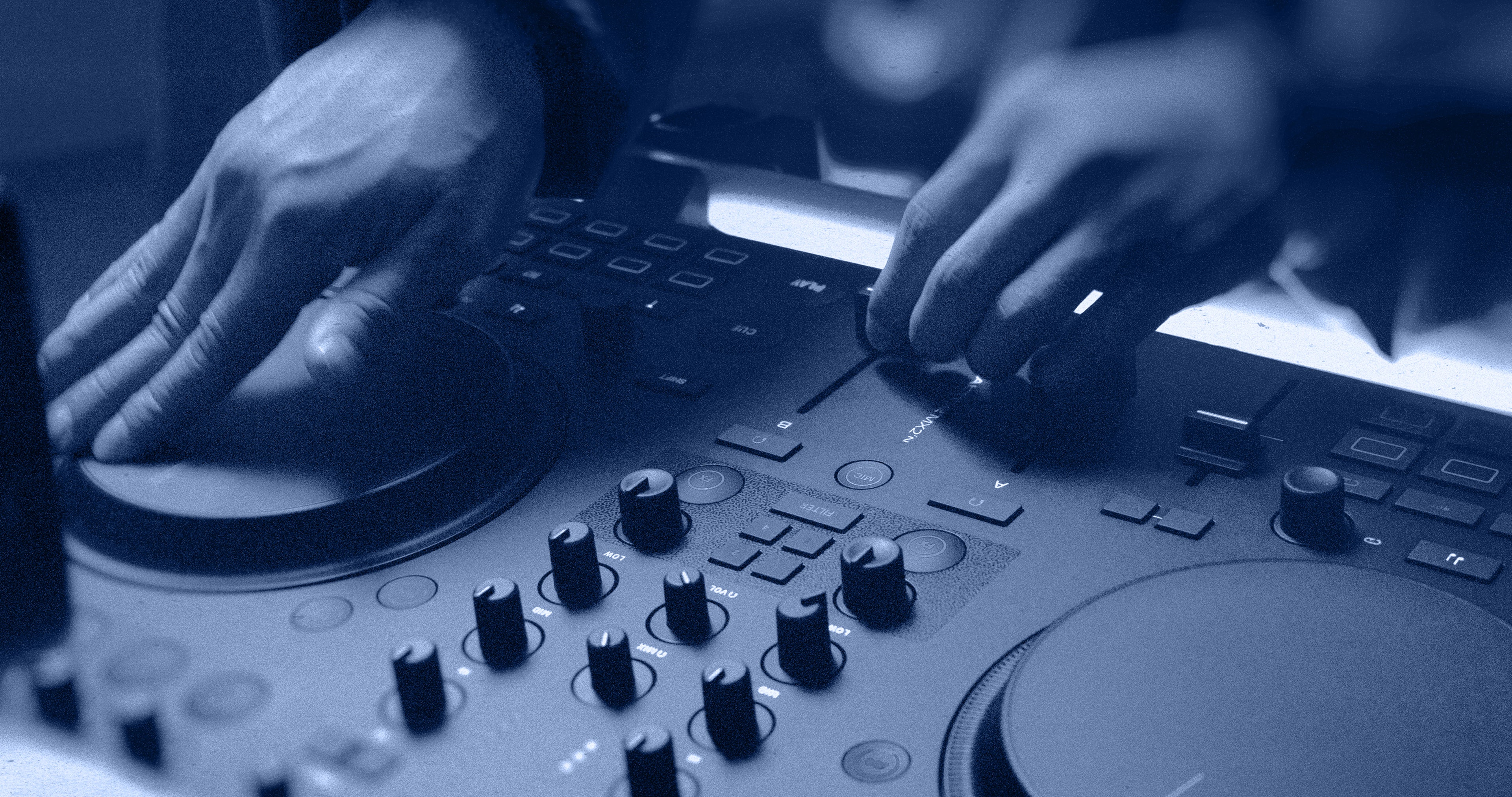 Native Instruments Traktor MX2 DJ controller with dual jog wheels, colorful performance pads, and various control knobs and faders.