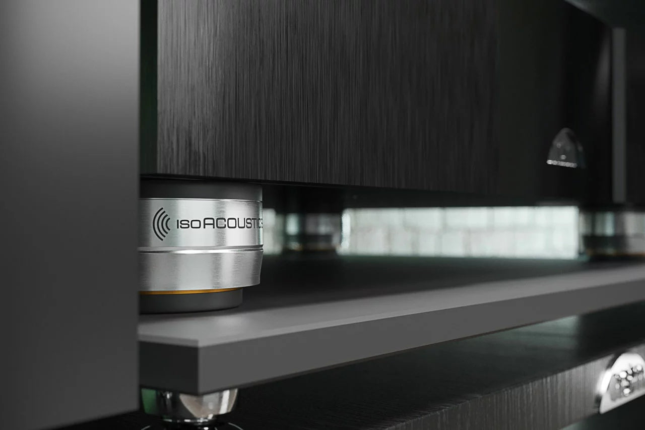 IsoAcoustics Orea Bronze speaker stands on a modern living room floor, supporting audio speakers with a sleek bronze finish.