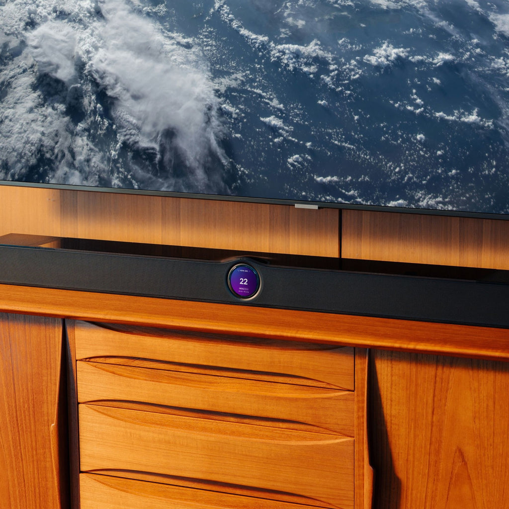 WiiM Bar Black in a living room beneath a wall-mounted TV