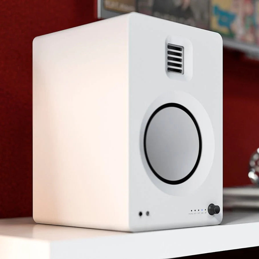 Kanto Audio TUK wireless speaker in white with fabric grille, compact design, and control buttons on top.