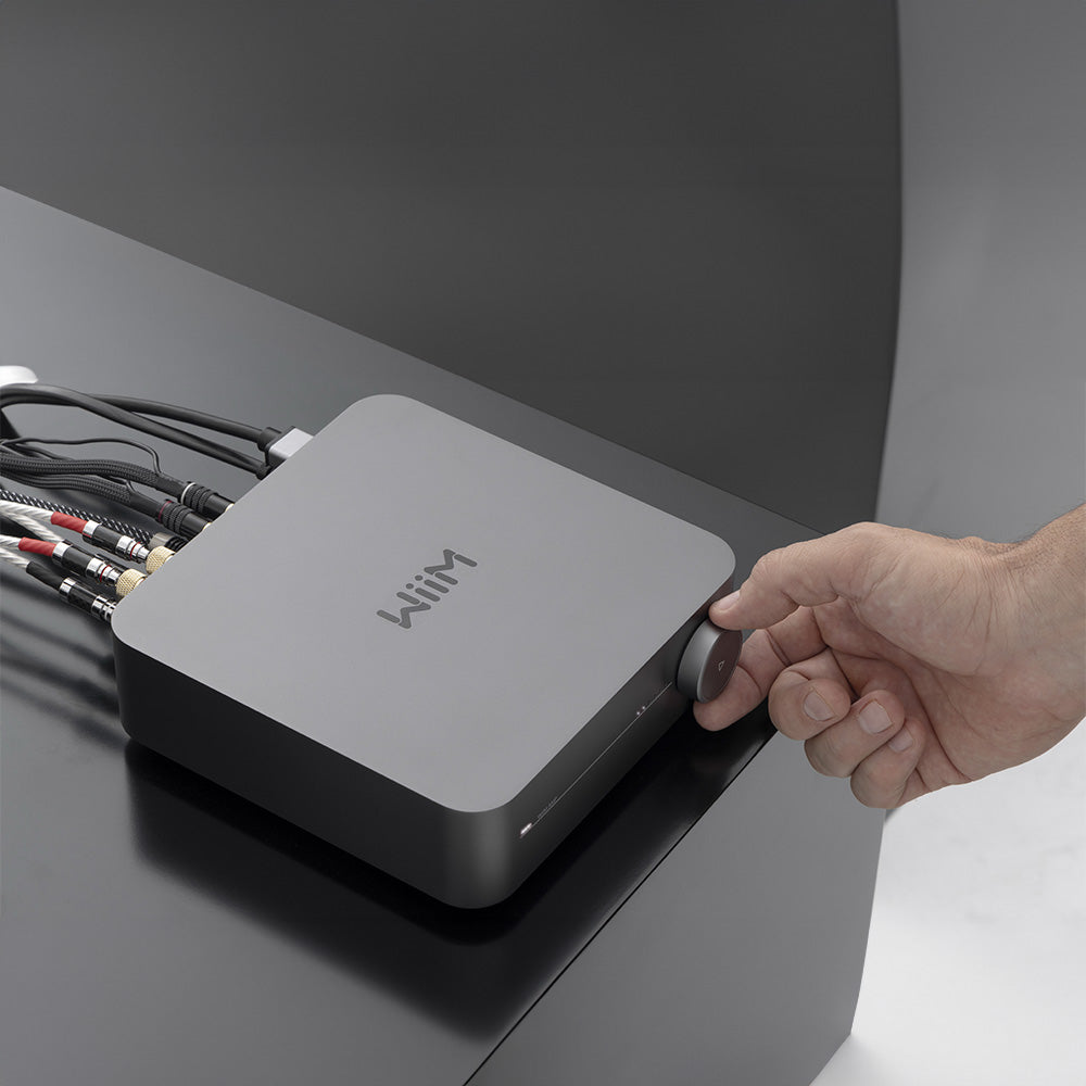 WiiM AMP music streamer device with sleek black design and control buttons, used for high-quality wireless audio streaming.